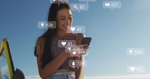 Smiling Woman Engaging on Social Media at Beach