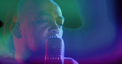 Singing soulful vocalist performing with retro microphone under neon stage lighting