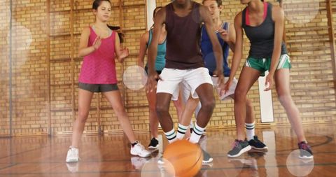 Teen basketball drill showing dribbling and defensive pressure in school gymnasium