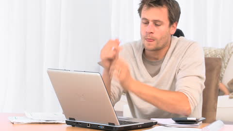 Man Struggling with Finances on Laptop in Modern Home