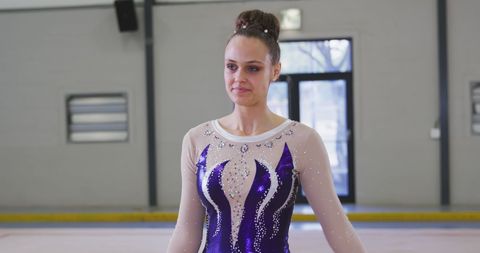 Focused Female Gymnast Wearing Detailed Costume in Sports Hall