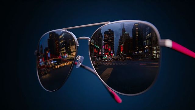 Floating mirrored aviator sunglasses reflecting neon city at night with pink temple tips
