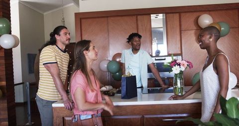 Group of Friends Celebrating Around Kitchen Island with Balloons