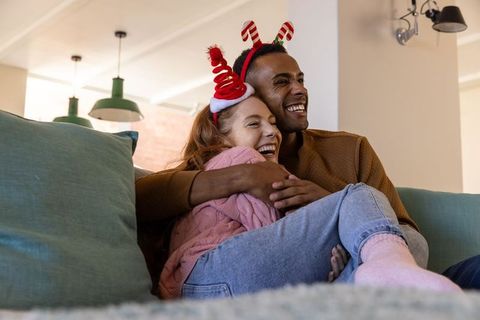 Joyful Couple Embracing on Sofa with Holiday Headbands