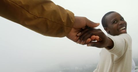 Joyful African American Couple Holding Hands on Misty Beach