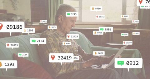 Senior man engaged with digital notifications on laptop at home