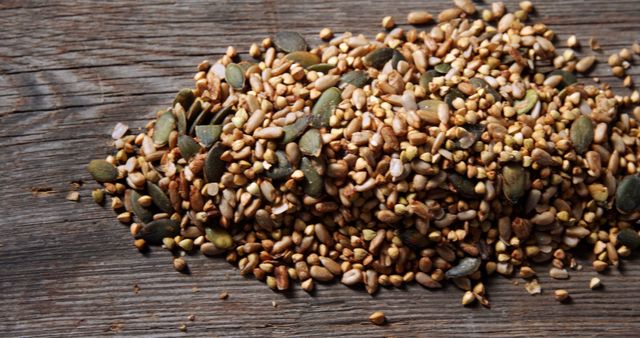 A mix of various seeds is scattered across a wooden surface, with copy space. These seeds, often used in healthy diets, provide a rich source of nutrients and can be added to a variety of dishes for added texture and flavor.