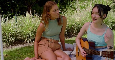 Young Women Enjoying Acoustic Guitar Outdoors on Blanket