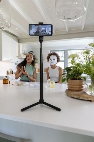 Beauty creator filming skincare tutorial with sheet mask at bright minimal kitchen island