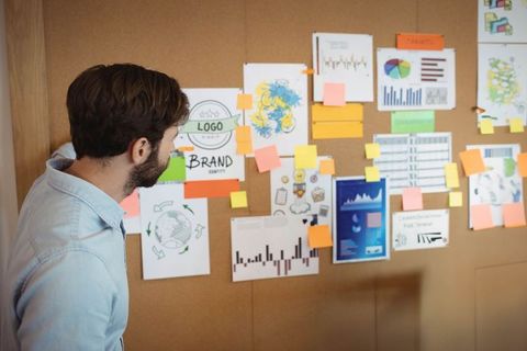 Creative professional analyzing brand concepts on corkboard
