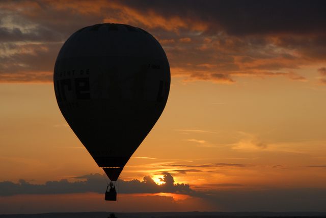 Silhouette of a hot air balloon floating gently across the sky with the warm glow of sunset on the horizon. Ideal for use in travel blogs, brochures promoting serene and adventurous getaways, posters depicting relaxation and tranquility, or promotional materials focusing on dreamy scenic landscapes.