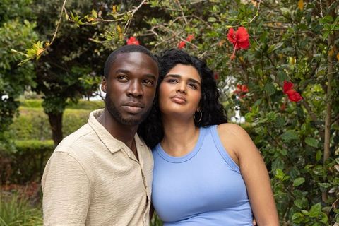 Mixed-ethnicity couple standing in garden wearing casual clothing, hibiscus bloom