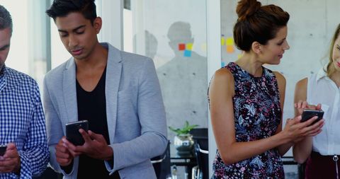 Diverse professionals engaged with smartphones in modern office