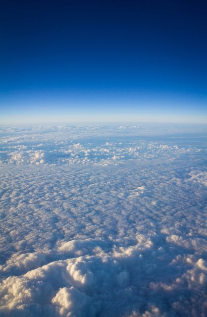 Stunning view of fluffy clouds and clear blue sky captured from an airplane at high altitude. Perfect for use in nature photography, travel promotions, aviation-related content, or as an inspiring background.