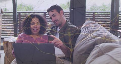 Couple collaborating on laptop at home with network overlay visualizing connected data