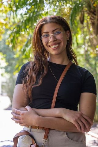 Sunlit portrait of african american woman smiling with glasses on tree-lined path