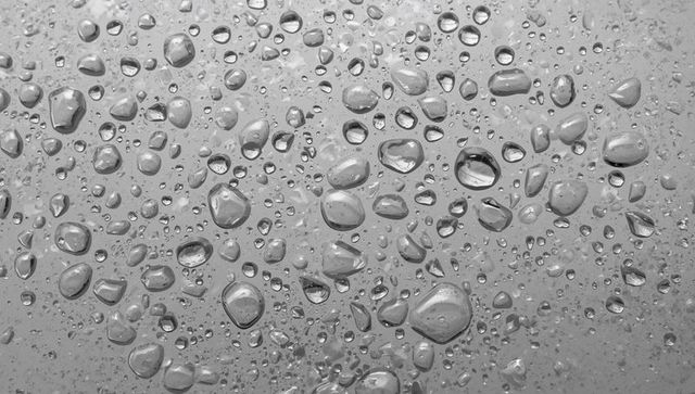 Close-up Water Droplets on Glass Pane Creating Reflective Macro Texture Pattern