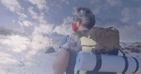 Solo hiker in snowy landscape with red face mask and backpack