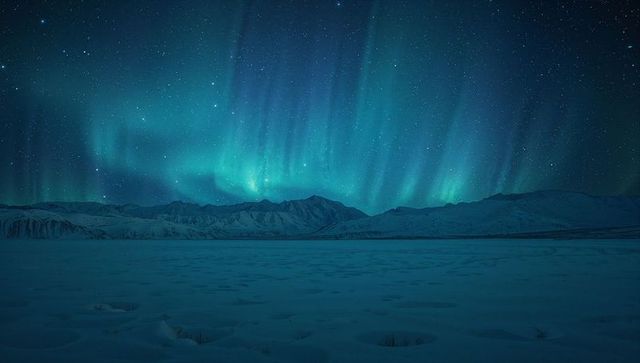 Dancing Aurora Curtains Glowing Above Snow-Covered Mountains Under Starry Arctic Sky