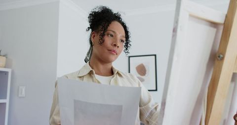 African american artist comparing print with canvas in home studio