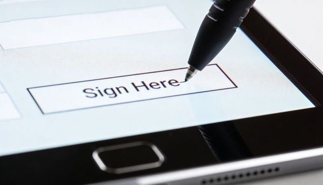 Closeup Stylus Signing Digital Form on Tablet Sign Here Field for E-signature and Security