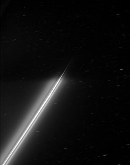 The strands of Saturn F ring disappear into the darkness of the planet shadow. Background stars make trails across the sky during the long exposure