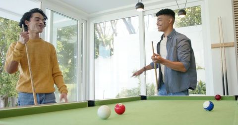 Two Friends Playing Pool in Sunlit Modern Living Room, Casual Billiards Lifestyle
