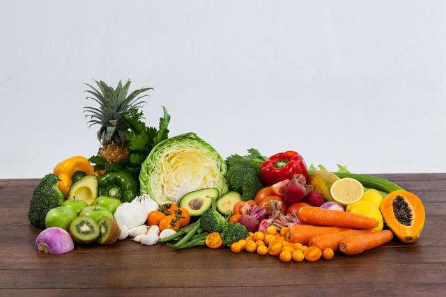 Close-up of a variety of fresh vegetables and fruits including cabbage, pineapple, peppers, broccoli, carrots, avocados, garlic, and more. Ideal for use in content related to healthy eating, diet planning, vegetarian or vegan recipes, and organic living. This image conveys the concept of fresh, nutritious, and colorful food, perfect for promoting a healthy lifestyle.