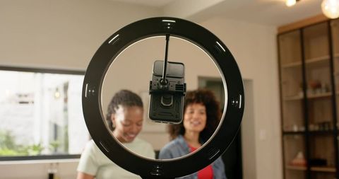 Multiracial female creators recording with ring light and smartphone mount in home studio