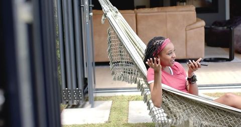 Woman Relaxing in Outdoor Hammock Checking Smartphone