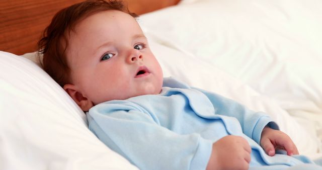 Adorable Baby Relaxing on Bed in Soft Blue Pajamas - Download Free Stock Images Pikwizard.com