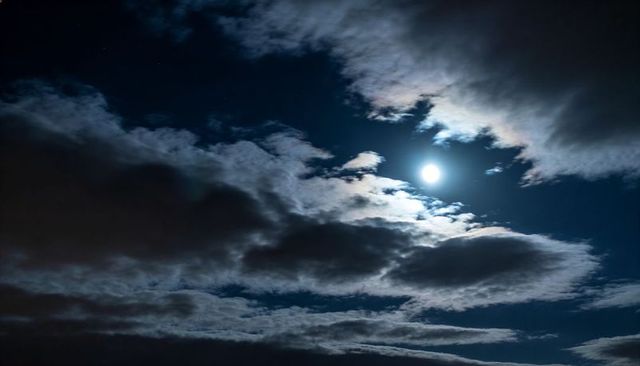 Moonlight Illuminating Layered Clouds with Silver Linings and Lunar Halo
