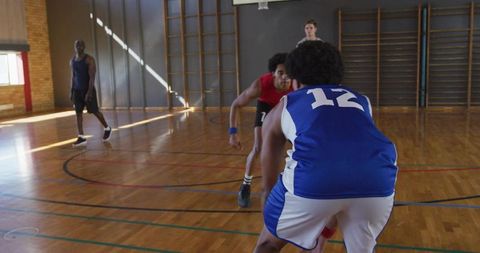 School Basketball Player Number 12 Dribbling While Defender Pressuring on Hardwood Court