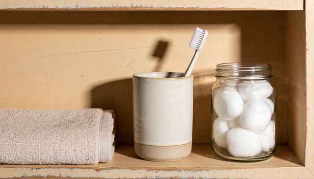 Minimalist bathroom vanity still life with toothbrush in ceramic cup and cotton ball jar