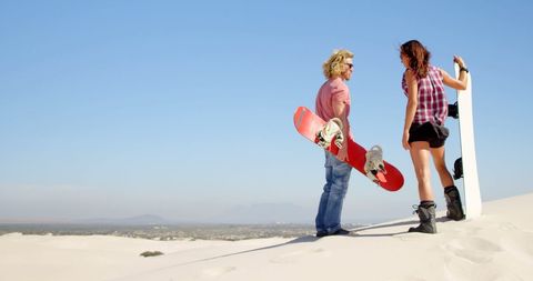 Caucasian Couple Preparing for Sandboarding on Sunny Day