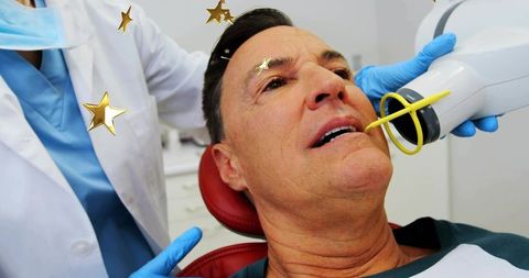 Senior man receiving dental x-ray with clinician holding yellow bite ring in clinic