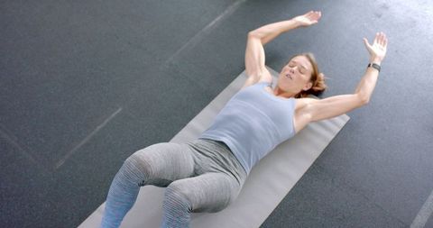 Dedicated Woman Exercising on Fitness Mat in Gym