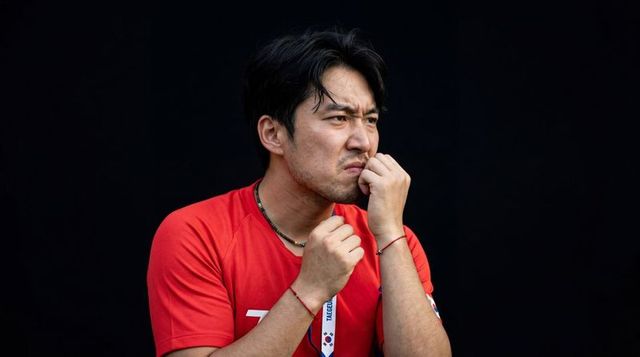 Tense man in red shirt pressing fingers to lips and biting nails expressing anxiety