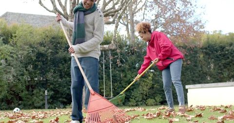 Mother and son bonding over autumn leaf raking in garden