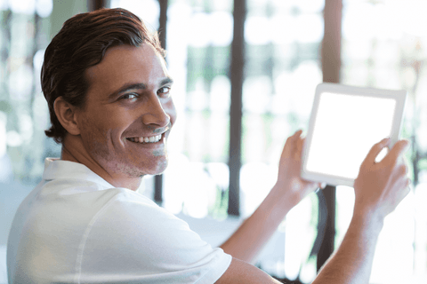 Smiling Man Holding Transparent Tablet in Modern Cafe
