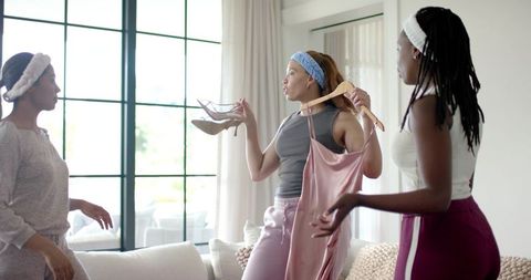 African american friends choosing satin dress and clear heels in bright living room home