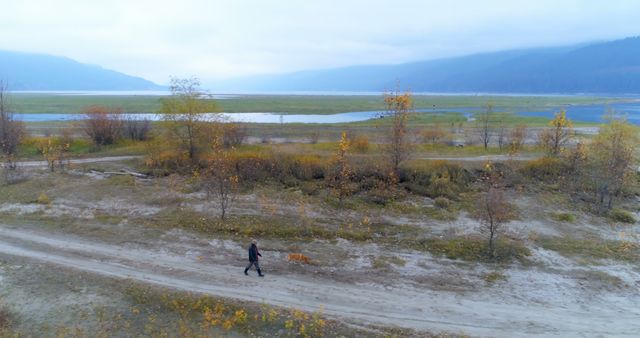 Solitary Man Walking Along Scenic Riverscape with Mountains - Download Free Stock Images Pikwizard.com