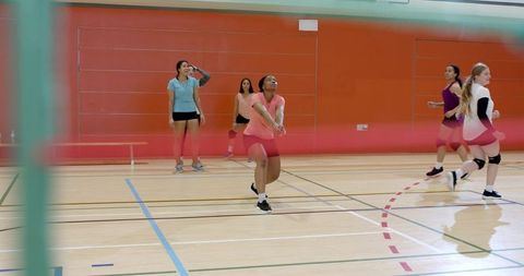 Female volleyball team practicing forearm pass with african american player leading rally