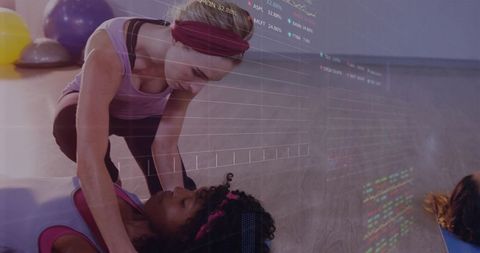 Instructor supporting client in mat stretch with exercise balls and data overlay