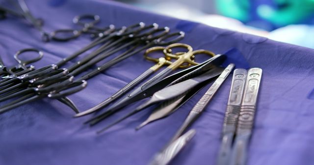 Sterile surgical instruments, including scissors, forceps, and other tools, are precisely arranged on a medical drape. This image can be used in healthcare documentaries, medical articles, hospital brochures, or surgical training materials to depict a professional and prepared operating environment.