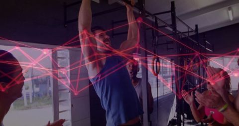 Mid-adult man completing pull-up while teammates cheering with red network overlay