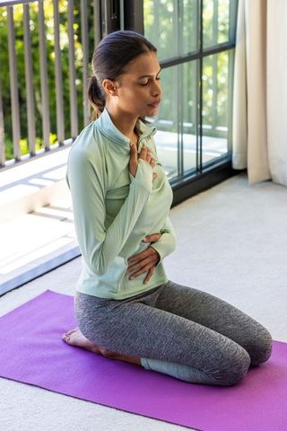 African american woman practicing mindful breathing on purple yoga mat for calm balance