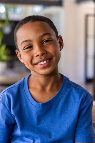 Smiling boy in blue t-shirt sitting in modern living room with soft-focus bokeh background