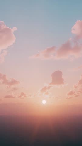 Vertical dawn video of sun disk rising through pastel pink clouds with soft rays