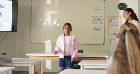 Teen girl presenting project in classroom with African American teacher encouraging students